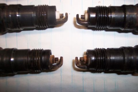 1990 Ford Bronco - A close-up view shows four spark plugs, likely removed from an engine for inspection or replacement.