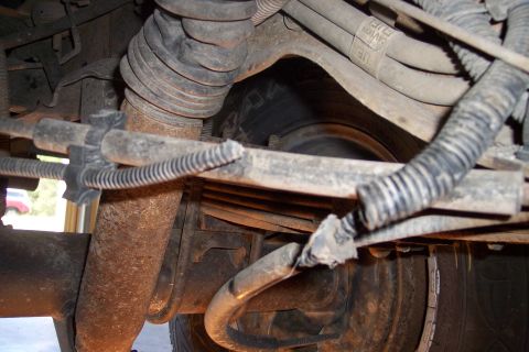 1990 Ford Bronco - Close-up of vehicle undercarriage showing suspension parts and electrical wiring.