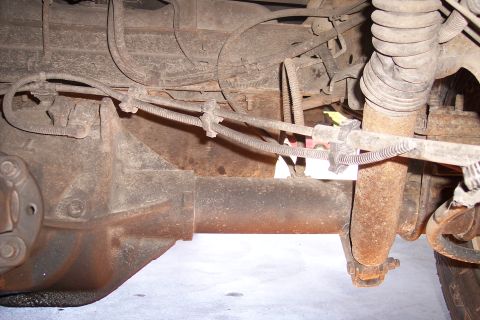 1990 Ford Bronco - Close-up view of the rear axle and suspension system, showing brake lines and a shock absorber.