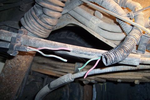 1990 Ford Bronco - Exposed wiring is visible on the undercarriage of a vehicle, near a tire.