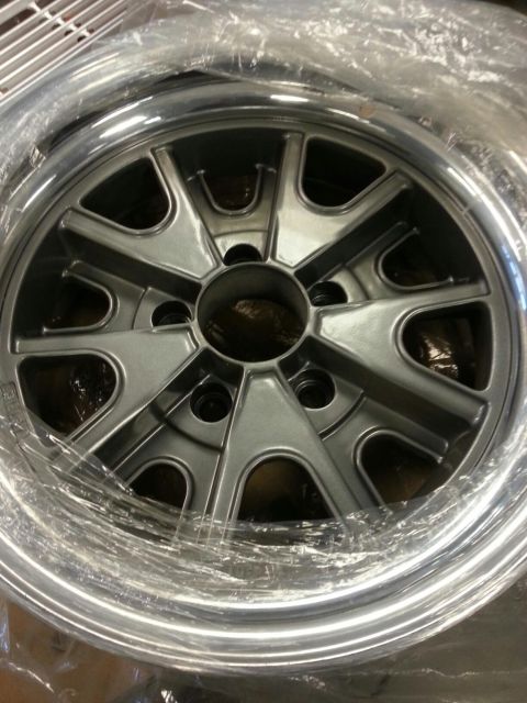 1964 Ford Fairlane - A single silver alloy wheel with a five-spoke design and polished rim is shown, partially covered in protective plastic wrap.