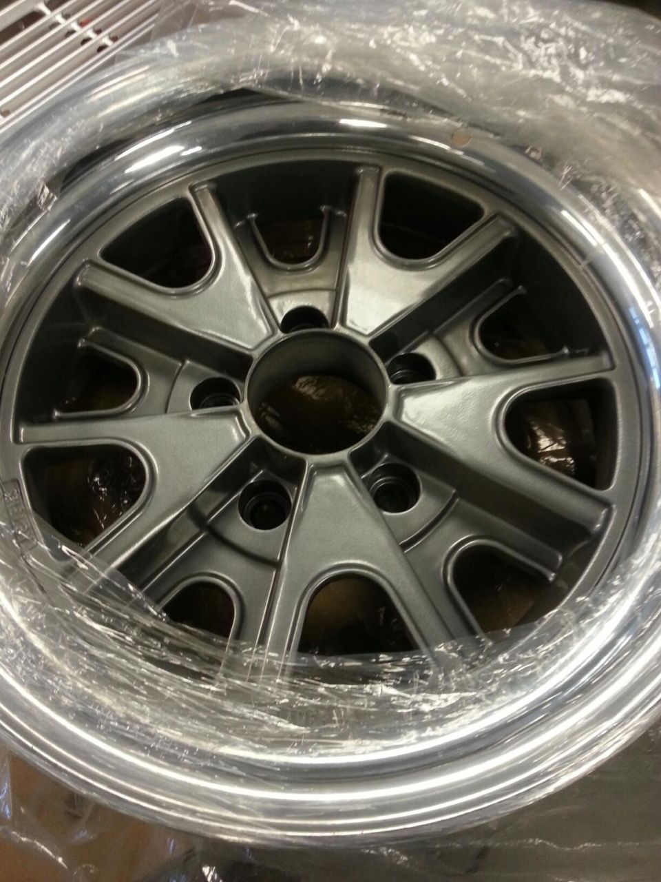 Silver alloy wheel with five spokes and a polished lip, wrapped in plastic