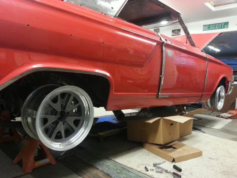 1964 Ford Fairlane - A red 1964 Ford Fairlane is shown on jack stands, possibly during a restoration, with new wheels installed.