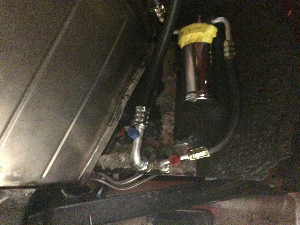 Custom fuel filter installation under a vehicle with chrome canister and metal lines.