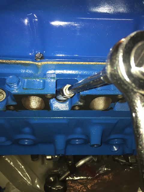 1978 Ford Bronco - A close-up shot shows a socket wrench being used to tighten a bolt on a blue painted engine block. The engine appears to be part of a class…
