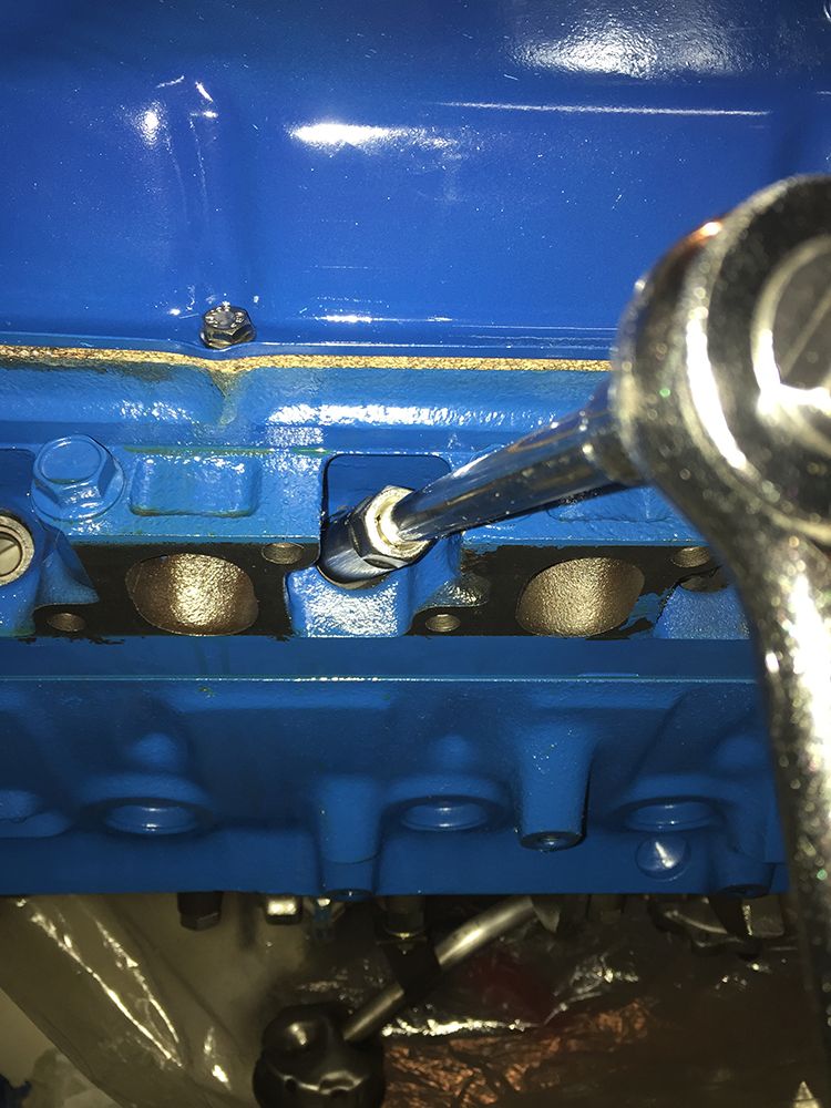 Socket wrench tightening a bolt on a blue engine block.