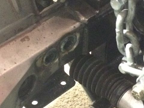 1964 Ford Fairlane - A close-up view shows the front chassis area of a vehicle, with two circular openings visible on a metal bracket. A black bellows boot and…