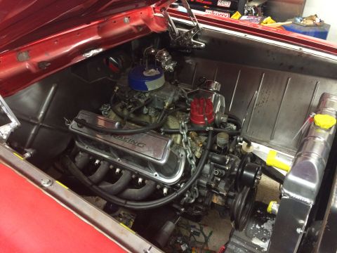 1964 Ford Fairlane - The engine bay of a red 1964 Ford Fairlane shows a V8 engine with chrome valve covers and a blue air filter. A large aluminum radiator is v…