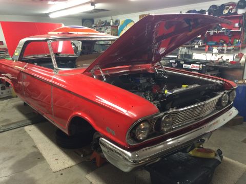 1964 Ford Fairlane - A red 1964 Ford Fairlane is shown in a garage with its hood and trunk open. The car is on jack stands and appears to be undergoing restorat…