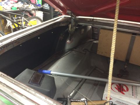 1964 Ford Fairlane - The open trunk of a classic car, possibly a 1964 Ford Fairlane, shows the interior with a black carpeted floor, a grey metal box on the lef…