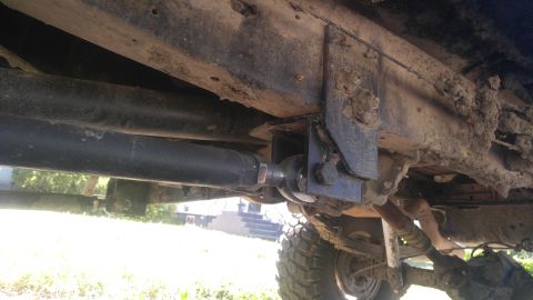 1991 Ford Bronco - The underside of a vehicle shows a heavily modified suspension system with a large metal bracket attached to the frame and a tie rod end co…
