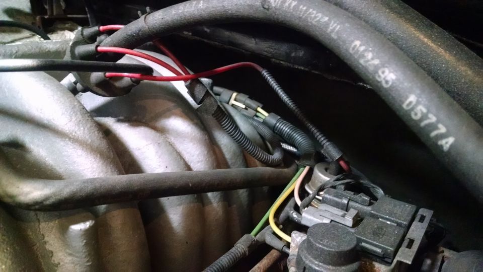Engine bay of a 1995 Ford Bronco with hoses, wires, and a sensor.