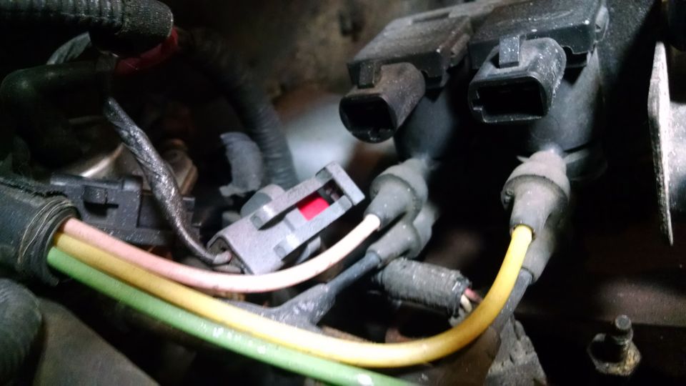 Close-up of engine wiring harness with green, yellow, and pink wires and electrical connectors.