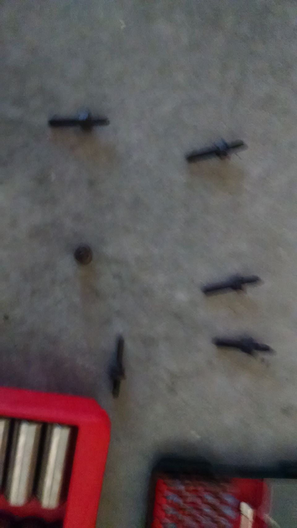Several small metal objects on a gray surface with a red toolbox.