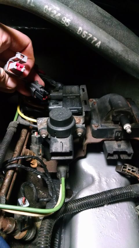 1995 Ford Bronco - A hand is shown disconnecting a wire harness connector from a black electronic component, likely part of the ignition system, in a 1995 For…