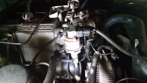 1995 Ford Bronco - A close-up view of the engine bay of a 1995 Ford Bronco, showing the throttle body, alternator, and various hoses and wiring.