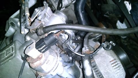 1995 Ford Bronco - A close-up view of engine components in a 1995 Ford Bronco, showing a throttle body, hoses, and electrical connectors.