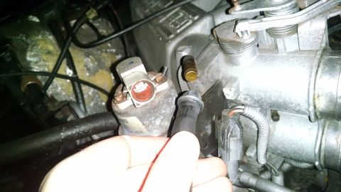 1995 Ford Bronco - A hand is holding a black vacuum hose near the throttle body of a Ford Bronco engine. Several electrical connectors and hoses are visible i…