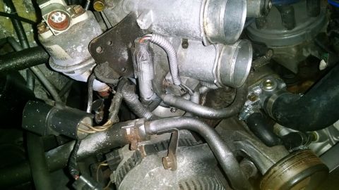 1995 Ford Bronco - A close-up view of the engine bay of a 1995 Ford Bronco, showing various hoses, sensors, and the throttle body.