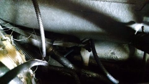 1995 Ford Bronco - This image shows a close-up view of the underside of a vehicle, focusing on various hoses, wiring conduits, and structural components. The…
