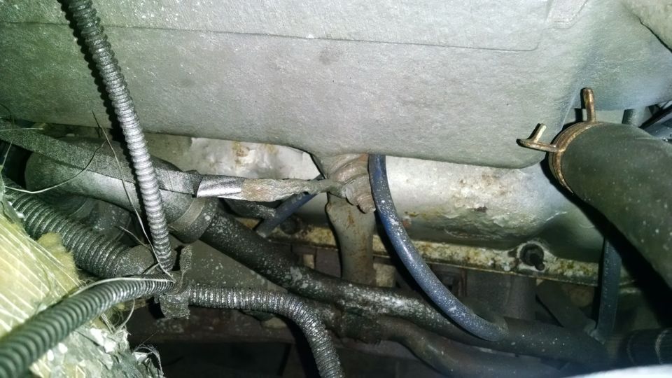 Engine bay of a 1995 Ford Bronco with hoses, wires, and metal components.