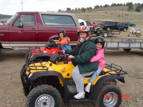 1996 Ford Bronco - A woman and two children ride on a yellow Honda ATV in front of a red Ford Bronco. The ATV has a rack on the back and the children are wear…