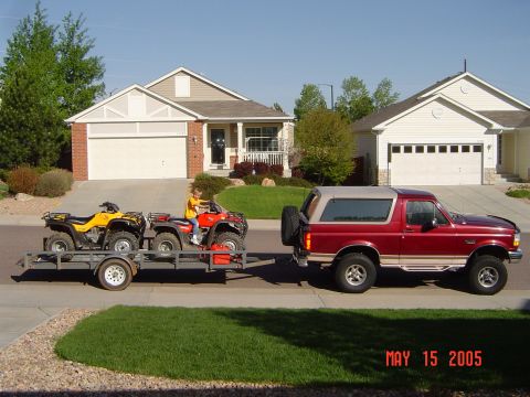 1996 Ford Bronco - A red 1996 Ford Bronco is parked on a street in front of a suburban house, towing a trailer with two ATVs. The image is dated May 15, 2005.