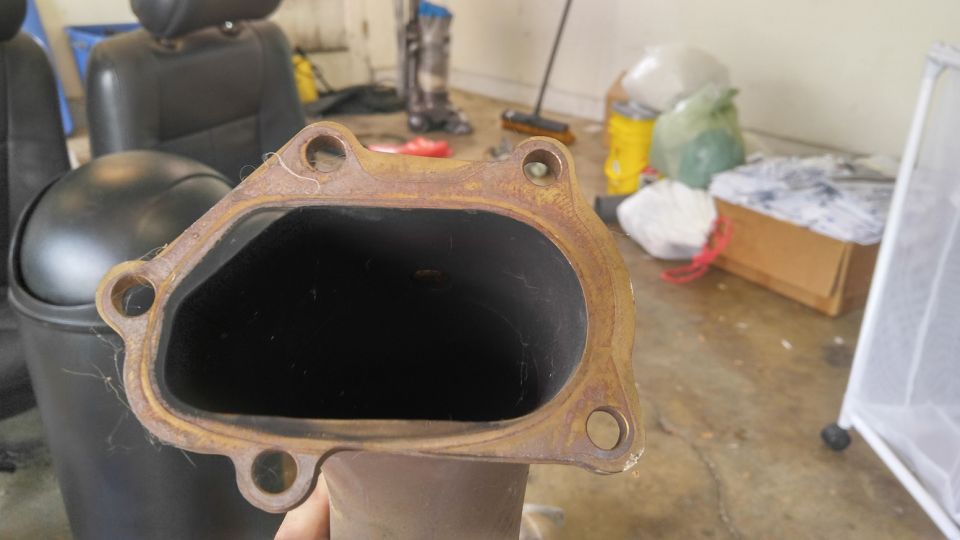 Rusty exhaust pipe flange with two bolt holes.