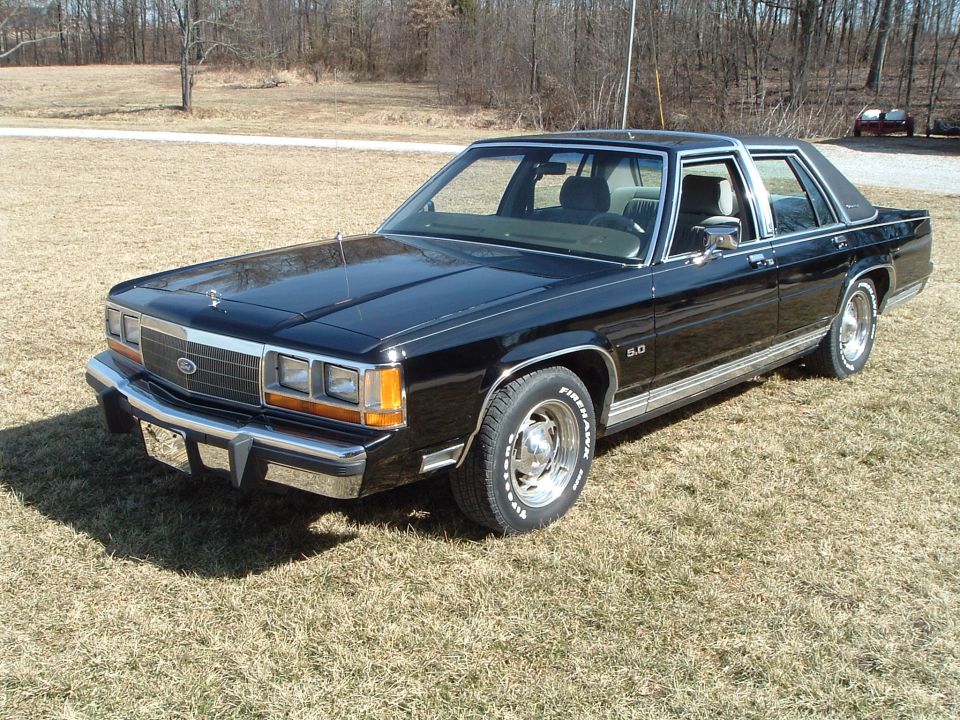 Black Ford LTD Crown Victoria sedan, front three-quarter view on dry grass