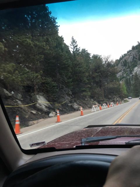 1996 Ford Bronco - View from the driver's seat of a maroon SUV driving on a mountain road with construction barriers and orange cones. The road is lined with…