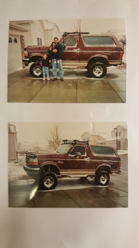 1996 Ford Bronco - A father holds his young daughter while standing next to his maroon Ford Bronco in a snowy driveway. The Bronco is a 1996 model with a two-…