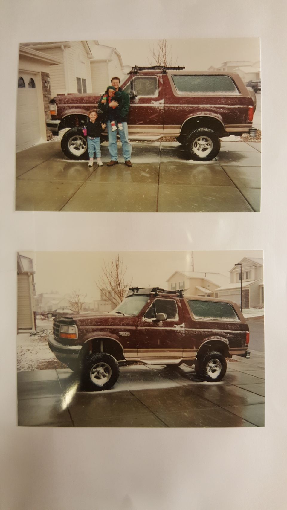 Father and daughter stand next to a maroon 1996 Ford Bronco in a snowy driveway.