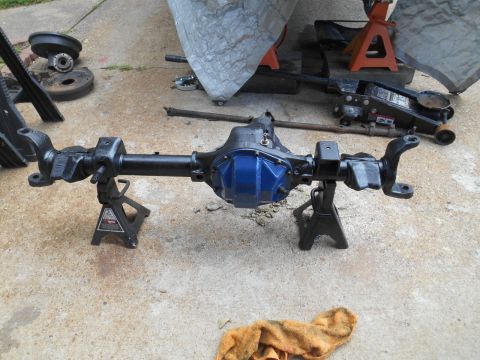 1972 Ford Bronco - A black rear axle assembly with a bright blue differential cover is supported by two black jack stands on a concrete surface. Various vehic…