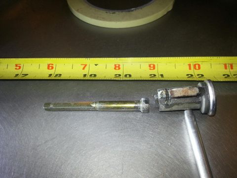 1964 Ford Fairlane - A disassembled metal mechanism is shown next to a yellow measuring tape with black markings. The mechanism appears to be a lock cylinder wi…