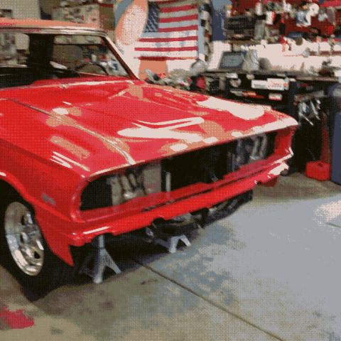 1964 Ford Fairlane - A red classic car, possibly a 1964 Ford Fairlane, is shown with its front end raised on jack stands in a garage. The car's hood is open, re…