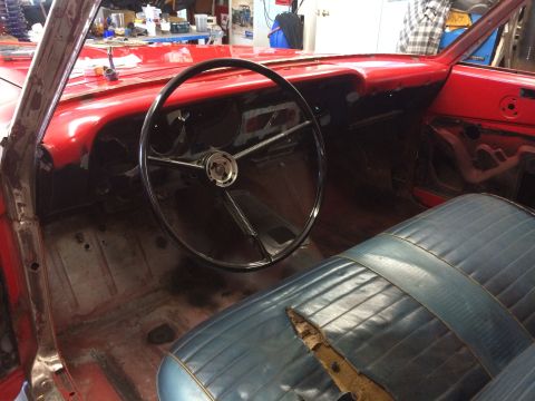 1964 Ford Fairlane - Interior view of a red classic car, likely a 1964 Ford Fairlane, showing the dashboard, steering wheel, and front seat. The car appears to…