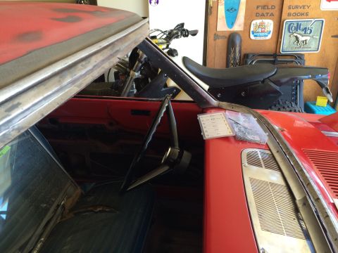 1964 Ford Fairlane - The interior of a red classic car, possibly a 1964 Ford Fairlane, is shown from a high angle looking down. A steering wheel, part of the da…