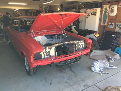 1964 Ford Fairlane - A red 1964 Ford Fairlane with its hood open is parked in a garage. A dog is lying on the floor next to the car.