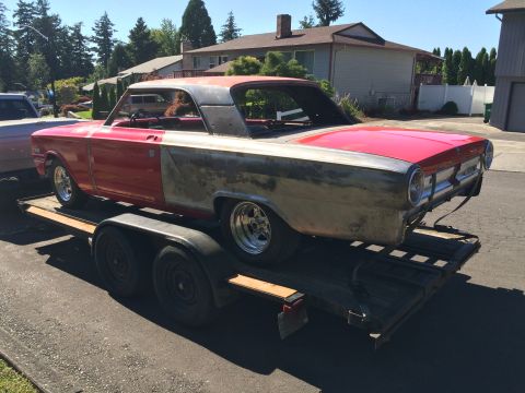 1964 Ford Fairlane - A red and unpainted classic car is loaded onto a flatbed trailer. The car appears to be a 1964 Ford Fairlane, with a two-tone paint scheme…
