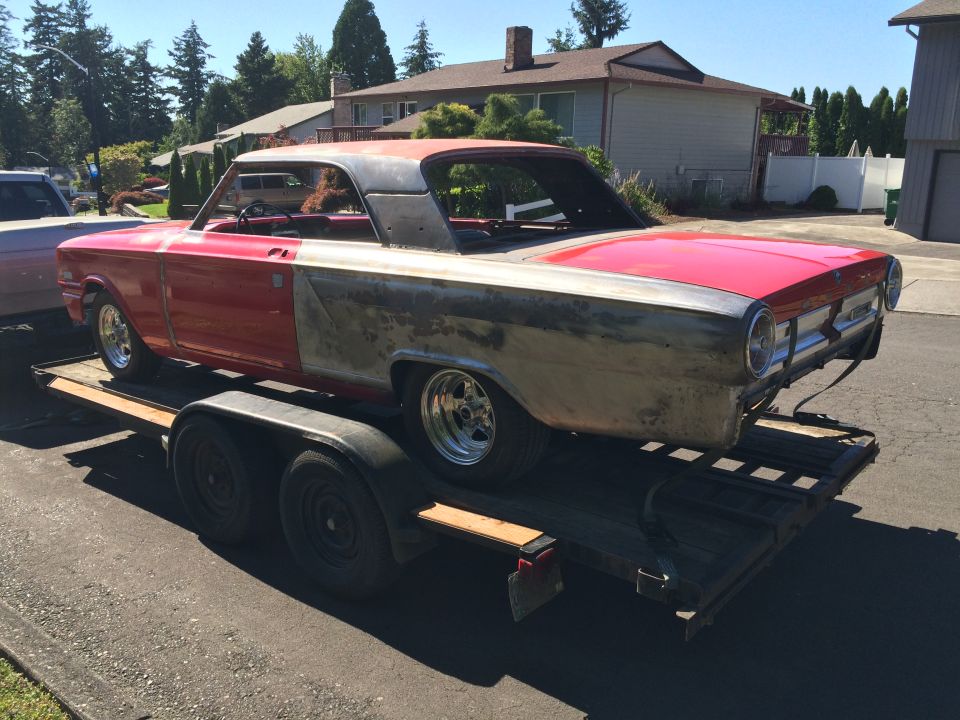 1964 Ford Fairlane on a trailer, red and unpainted, custom wheels