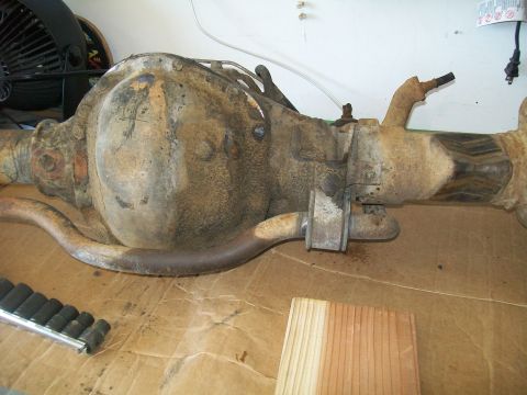 1991 Ford Bronco - A heavily rusted Ford Bronco rear differential assembly is shown resting on a cardboard surface. The assembly includes the differential hou…