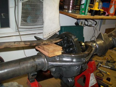 1991 Ford Bronco - A close-up view of an open differential housing, likely from a 1991 Ford Bronco, supported by a red jack stand. Tools and other automotive…