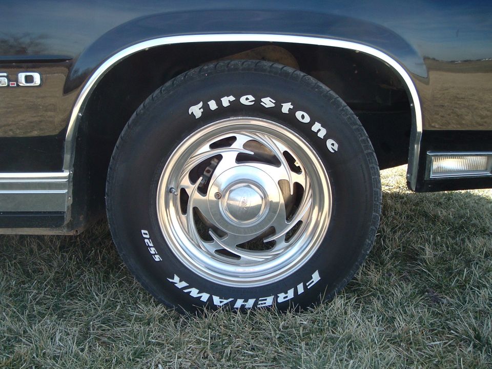 Close-up of Firestone Firehawk tire on polished slotted alloy wheel under black fender