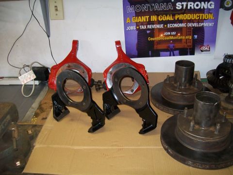 1991 Ford Bronco - Two red and black brake caliper assemblies are displayed on a cardboard surface, with several brake rotors and hubs visible in the backgrou…