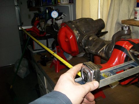 1991 Ford Bronco - A person is using a tape measure and a level to measure a red-painted differential housing that is mounted on red jack stands. A yellow tap…