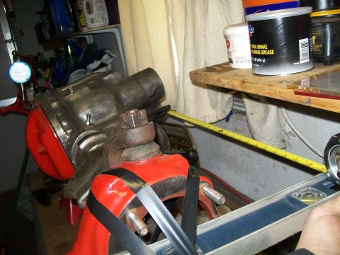 1991 Ford Bronco - A mechanic's measurement setup with a large metal component, possibly a differential housing, secured in a red vise. A yellow measuring tap…