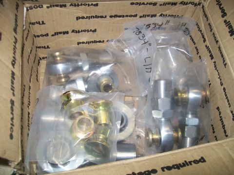 1991 Ford Bronco - A cardboard box filled with various metal automotive parts, mostly spherical rod ends and bushings, some still in plastic packaging. The bo…