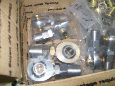 1991 Ford Bronco - A cardboard box filled with various metal automotive parts, including rod ends and spherical bearings, some of which are still in plastic p…