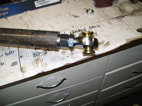 1991 Ford Bronco - A close-up view of a metal rod with a heim joint attached, resting on a workbench with handwritten notes. The rod appears to be part of a v…