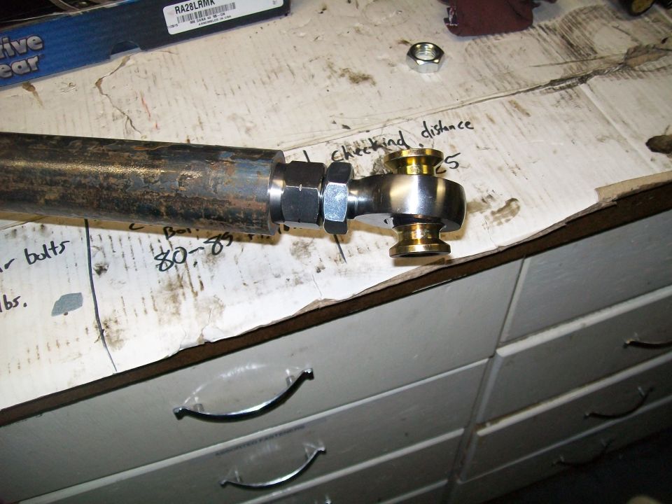 Metal rod with heim joint on a workbench with handwritten notes.
